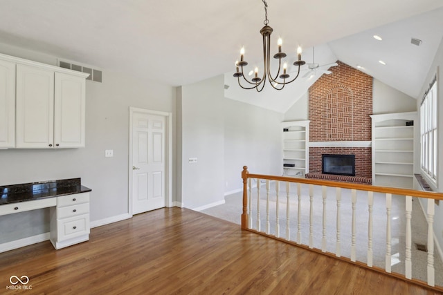 kitchen with visible vents, wood finished floors, white cabinetry, baseboards, and a brick fireplace