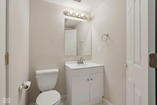 half bath with a textured ceiling, toilet, vanity, and baseboards