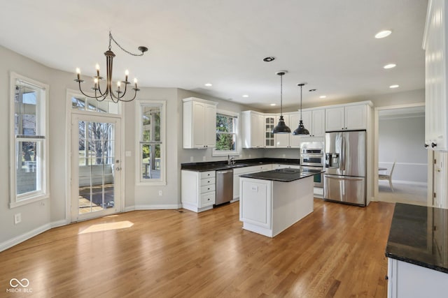 kitchen with dark countertops, white cabinets, stainless steel appliances, and light wood-style floors