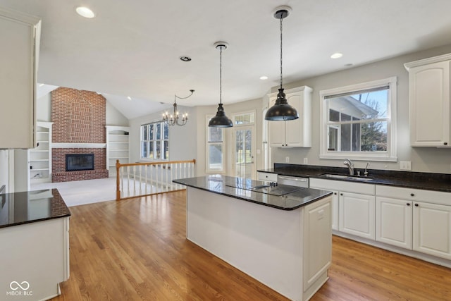 kitchen featuring a sink, open floor plan, a center island, white cabinetry, and light wood-style floors