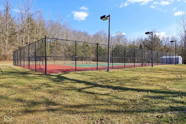 view of tennis court with a lawn, community basketball court, and fence