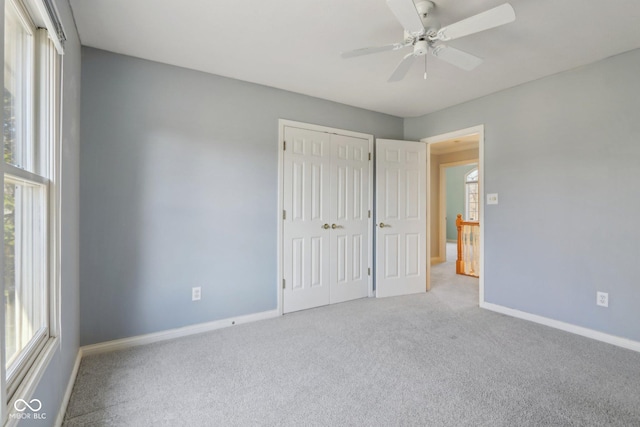 unfurnished bedroom with multiple windows, carpet flooring, and baseboards