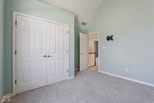 unfurnished bedroom featuring visible vents, baseboards, carpet, lofted ceiling, and a closet