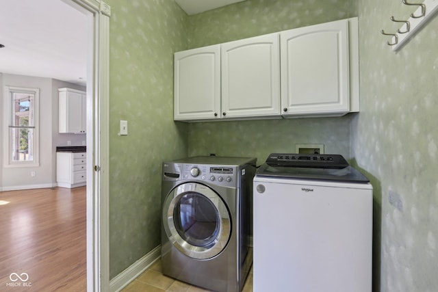 laundry room featuring separate washer and dryer, cabinet space, baseboards, and light wood-type flooring