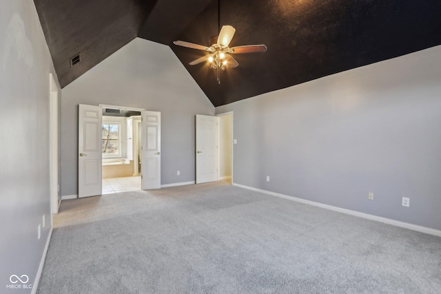 unfurnished bedroom featuring visible vents, light carpet, high vaulted ceiling, ensuite bath, and baseboards