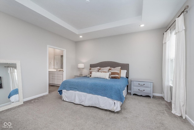 carpeted bedroom with ensuite bathroom, a tray ceiling, recessed lighting, and baseboards