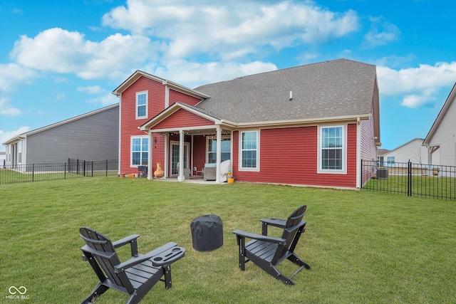 back of house with a fire pit, a lawn, a patio, a fenced backyard, and roof with shingles