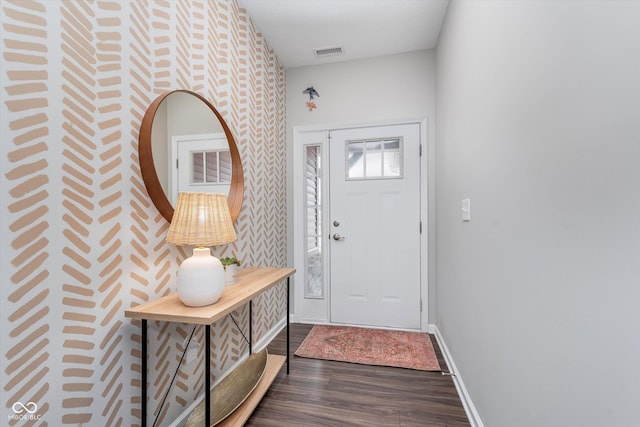 foyer with baseboards, visible vents, and dark wood-type flooring