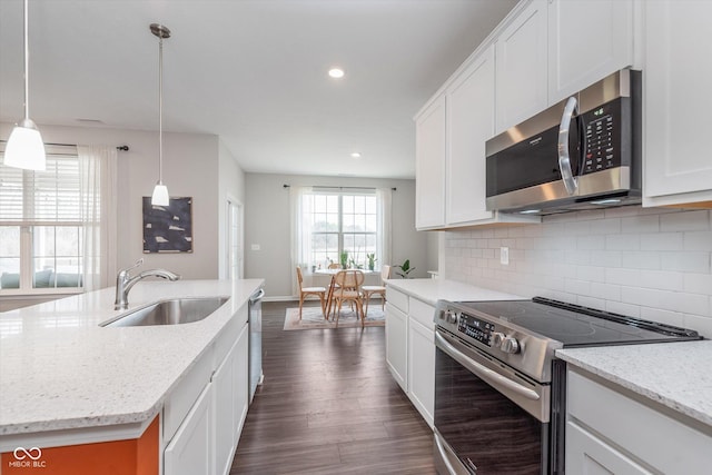 kitchen with dark wood-style flooring, a sink, white cabinetry, appliances with stainless steel finishes, and tasteful backsplash