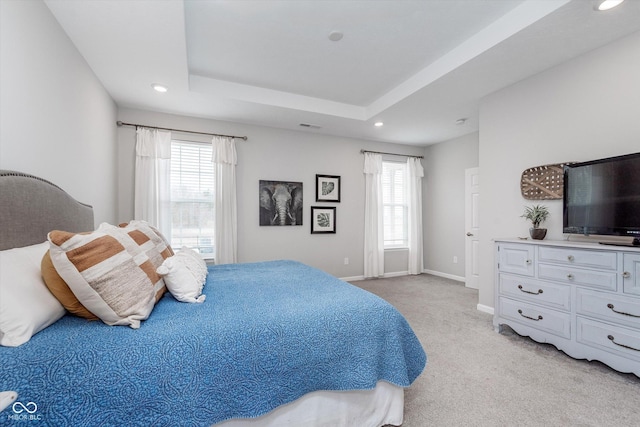 bedroom featuring baseboards, multiple windows, a tray ceiling, and light colored carpet