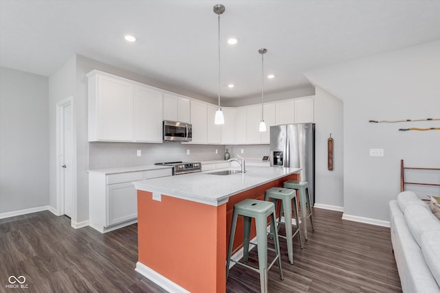 kitchen featuring stainless steel appliances, a breakfast bar, dark wood-style flooring, a sink, and backsplash