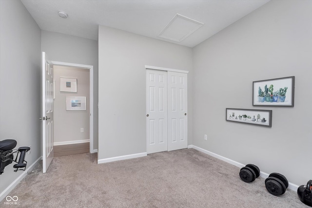 carpeted bedroom with a closet, attic access, and baseboards