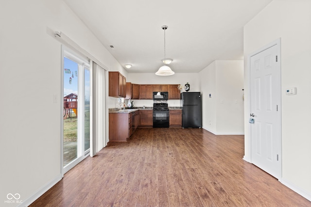 kitchen featuring pendant lighting, hardwood / wood-style floors, and black appliances