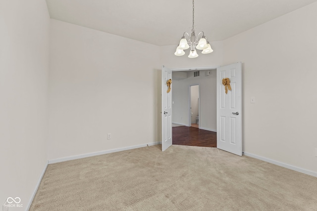 unfurnished room with an inviting chandelier and carpet flooring