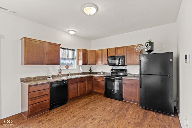 kitchen featuring hardwood / wood-style flooring, sink, and black appliances