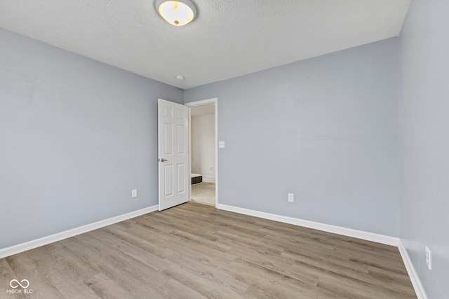 empty room with light hardwood / wood-style flooring and a textured ceiling