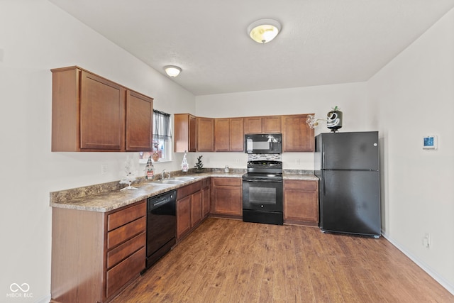 kitchen with wood-type flooring, sink, and black appliances