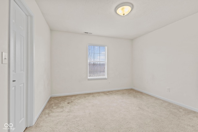 unfurnished room featuring light carpet and a textured ceiling