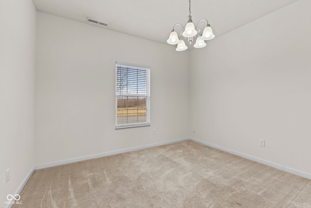 carpeted spare room featuring a notable chandelier