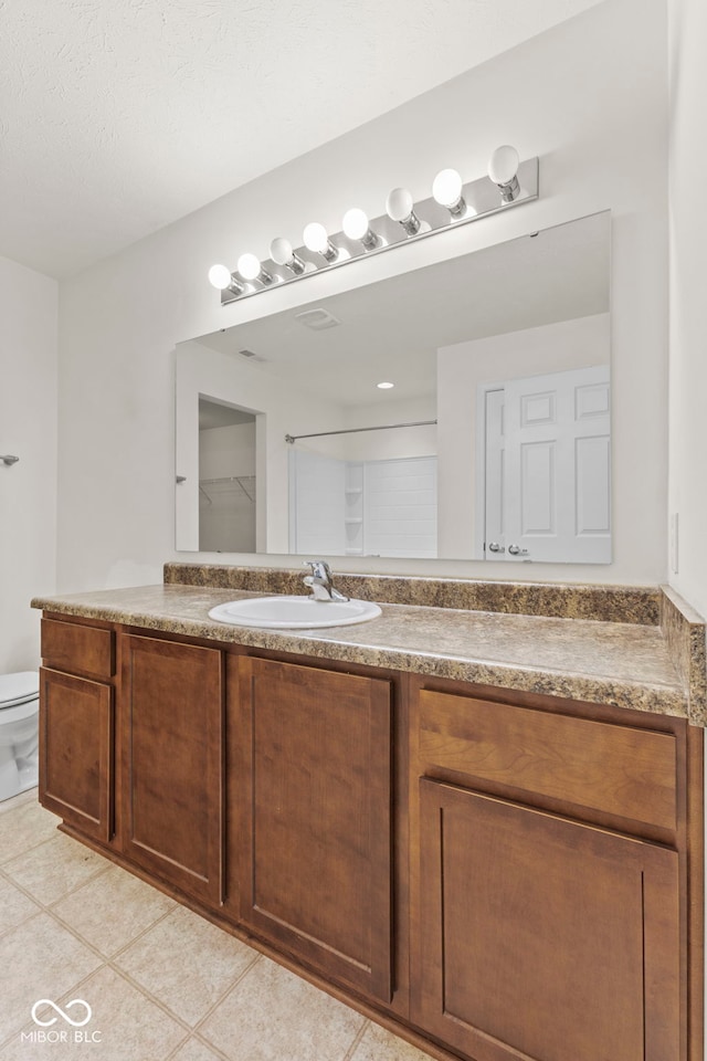 bathroom with tile patterned flooring, vanity, and toilet