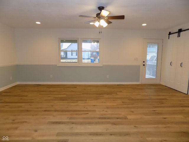 empty room featuring light hardwood / wood-style flooring, a barn door, and a wealth of natural light