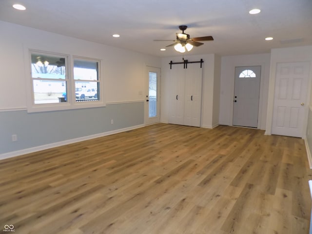 foyer with ceiling fan, light hardwood / wood-style floors, and a barn door