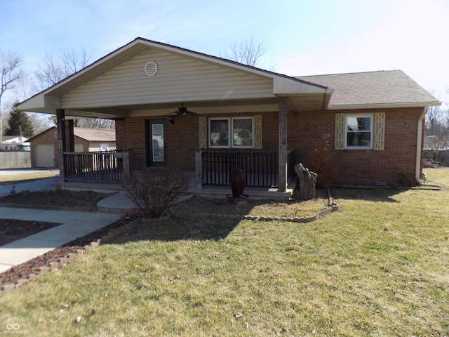 view of front of property with brick siding, a ceiling fan, an outbuilding, covered porch, and a front yard