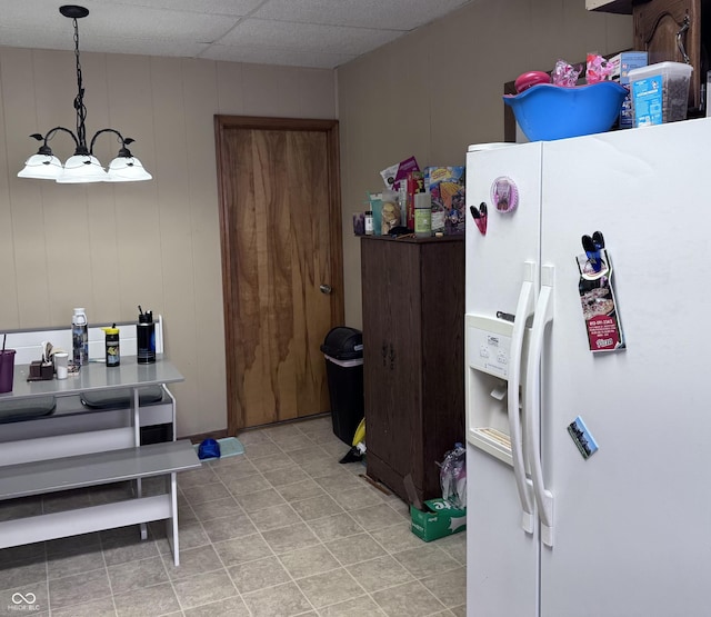 kitchen with white fridge with ice dispenser, a paneled ceiling, and decorative light fixtures