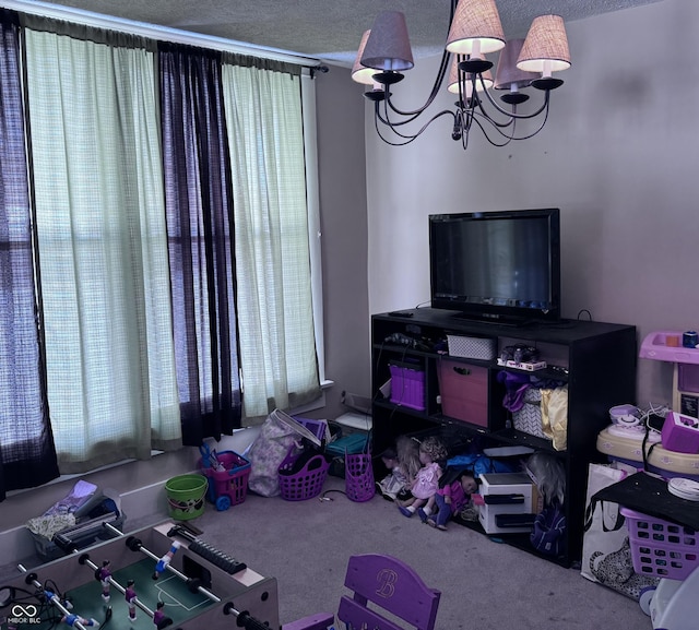 playroom featuring an inviting chandelier, carpet floors, and a textured ceiling