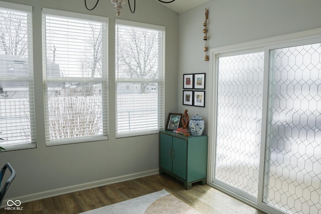 doorway featuring a healthy amount of sunlight, vaulted ceiling, baseboards, and wood finished floors