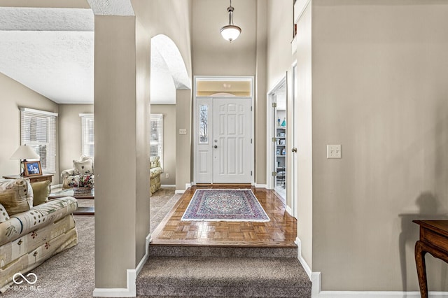 foyer with parquet flooring, a textured ceiling, and a high ceiling