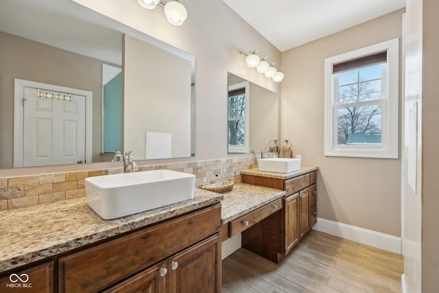 full bathroom featuring plenty of natural light, vanity, baseboards, and wood finished floors