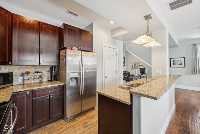 kitchen with pendant lighting, visible vents, appliances with stainless steel finishes, a sink, and an island with sink