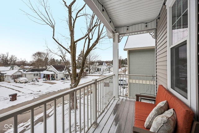 snow covered back of property with a sunroom and a residential view