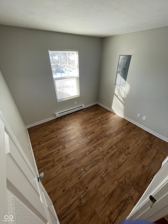 empty room with a baseboard heating unit, electric panel, and dark hardwood / wood-style floors