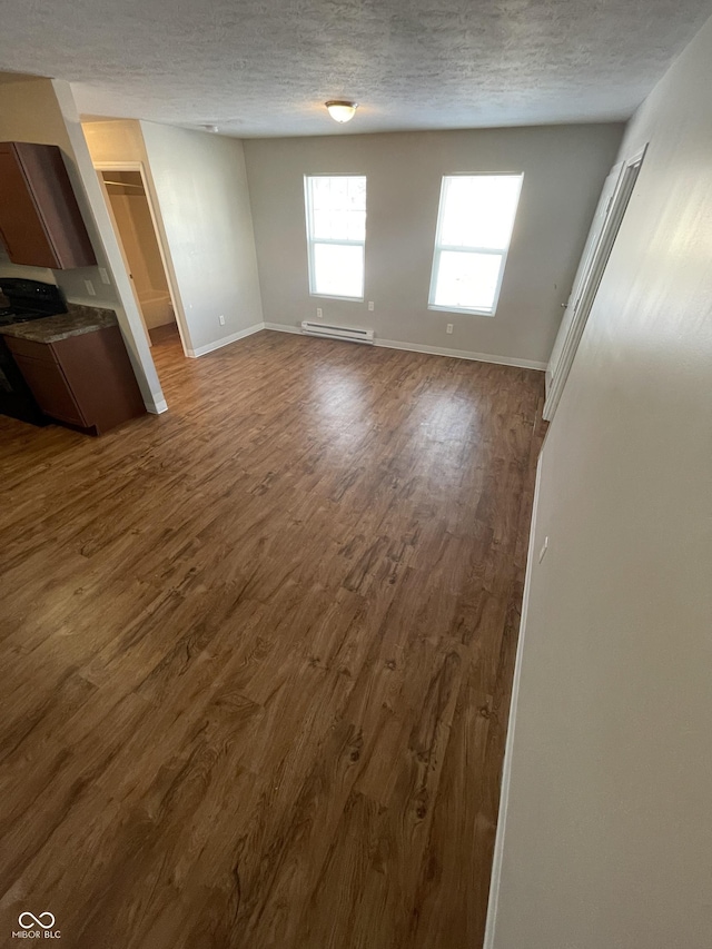 unfurnished living room featuring wood-type flooring, a textured ceiling, and a baseboard radiator