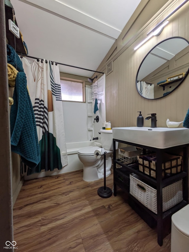 bathroom with shower / bath combination with curtain, lofted ceiling, wood-type flooring, and toilet