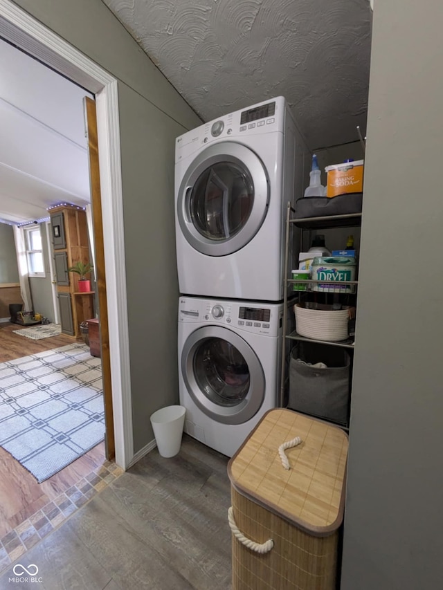 clothes washing area with hardwood / wood-style flooring and stacked washing maching and dryer