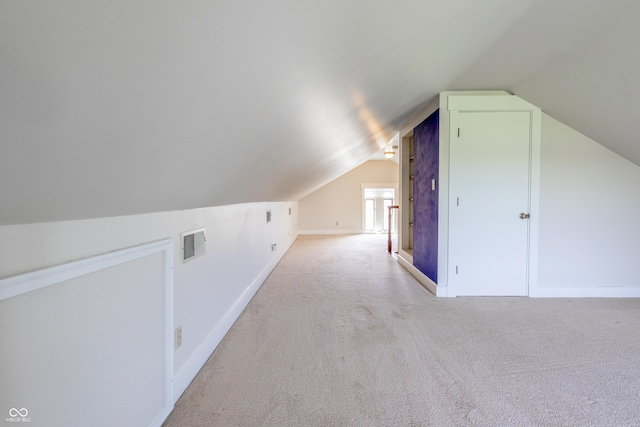 additional living space featuring visible vents, light colored carpet, baseboards, and lofted ceiling