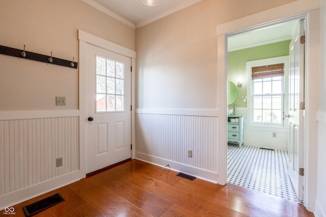 entryway with wood finished floors, visible vents, and a wainscoted wall