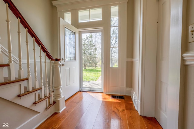 foyer with visible vents, light wood-style flooring, stairway, and plenty of natural light