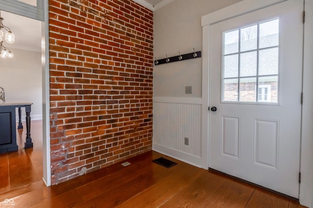 doorway to outside with crown molding, wainscoting, and wood finished floors