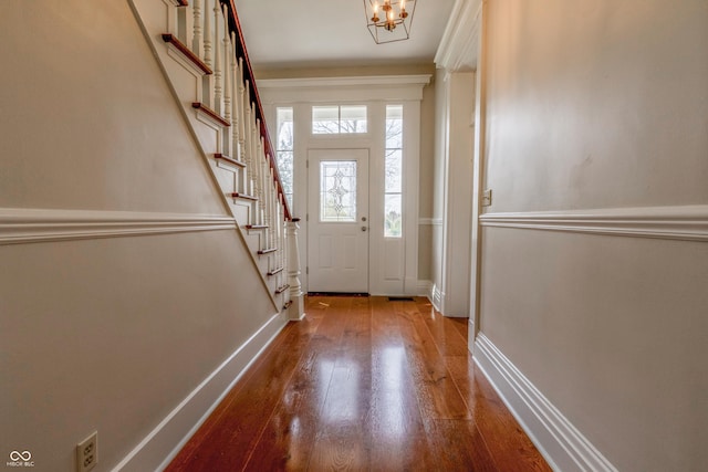 doorway featuring stairway, wood-type flooring, baseboards, and a notable chandelier