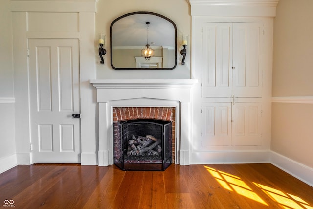 interior details with a brick fireplace, baseboards, and wood finished floors