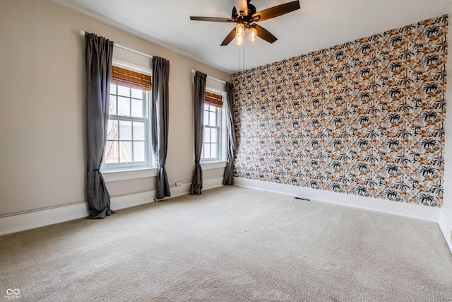 carpeted spare room with baseboards and a ceiling fan