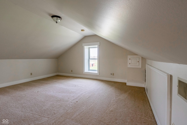 additional living space featuring light colored carpet, baseboards, and vaulted ceiling