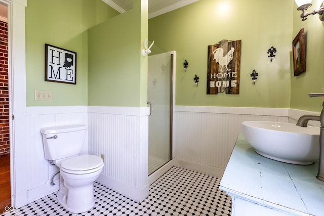 bathroom featuring ornamental molding, toilet, a shower stall, vanity, and a wainscoted wall
