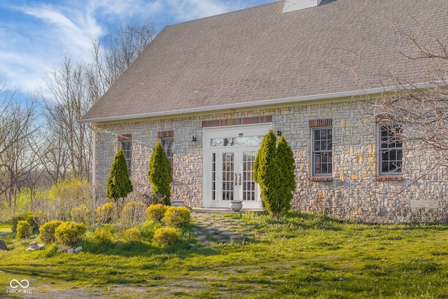 exterior space with roof with shingles, french doors, and stone siding