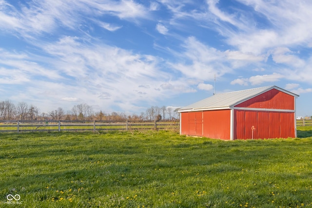 view of yard featuring a rural view, fence, an outbuilding, and a pole building