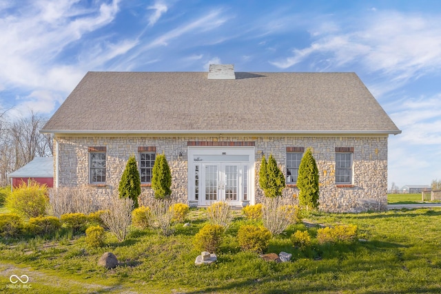 back of house with roof with shingles, french doors, stone siding, and a chimney